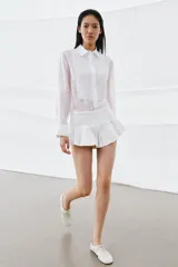 Camisa de corte fluido con cuello solapa y manga larga con puños. Presenta detalles de bordados a tono en el frente y cierre frontal con botones ocultos bajo solapa.