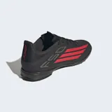 Championes de fútbol Adidas F50 League para césped artificial, color negro con detalles en rojo y blanco. Presentan un empeine de Fiberskin con estampado Sprintgrid y lengüeta envolvente para un ajuste ceñido.