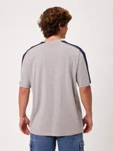 Remera negra de manga corta con diseño deportivo, parte superior de las mangas en color gris con ribete blanco y estampa frontal con la marca Rusty.