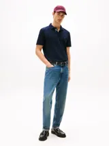 Chomba azul marino de corte regular Tommy Hilfiger, confeccionada en tejido piqué de algodón orgánico con cuello tipo chomba y cartera de dos botones. Presenta detalles distintivos de la marca y logo bordado en el pecho.