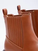 Bota tipo Chelsea de símil cuero color suela, con plataforma oscura, punta cuadrada y paneles elásticos laterales.