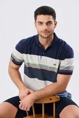 Remera polo de manga corta con diseño de franjas horizontales en tonos azul, beige, verde y terracota. Presenta cuello camisero con cierre frontal de dos botones y un pequeño bordado en el pecho.