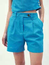 Short de vestir celeste con pinzas delanteras y cierre con botón.