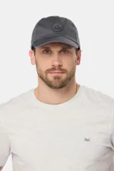 Gorro de béisbol azul de lona con visera curva y parche circular con logo bordado en el frente.