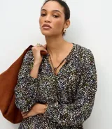 Vestido midi de corte fluido con estampado floral, escote en V con cordones ajustables, mangas largas abullonadas y falda con volados en el ruedo.