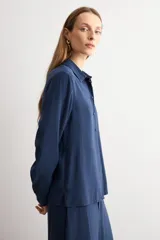 Camisa de corte clásico y calce holgado, con cuello camisero, cierre frontal de botones y mangas largas con puños abotonados.