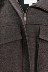 Chaqueta estilo bomber de color gris oscuro, con cuello subido, manga larga y corte holgado. Presenta bolsillos delanteros con solapa, bajo con pliegues y cierre frontal con cremallera oculta y botones a presión.