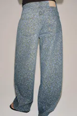 Jeans de tiro medio con corte barrel, confeccionados en denim con estampado floral integral. Presentan diseño de cinco bolsillos, cintura con trabillas y cierre frontal con cremallera y botón.