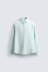 Camisa de corte relajado confeccionada en tejido de lino, con cuello solapa, manga larga con puños abotonados y cierre frontal de botones.