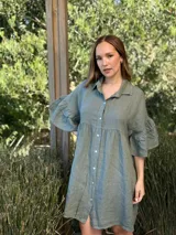 Vestido camisero blanco de lino italiano, con cuello camisero, cierre frontal con botones, mangas cortas con doble volado y bolsillos laterales.