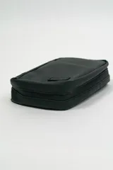 Bolso portadocumentos negro rectangular con cierre de cremallera y detalle de costura diagonal en el frente. Incluye logo "DREAM" en la parte inferior.