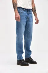 Jean de corte tapered, holgado en la cadera y levemente ajustado hacia los tobillos, con tiro medio y cierre frontal con botones.