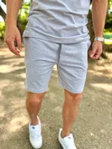 Conjunto deportivo gris melange compuesto por remera de manga corta y short con cordón ajustable en la cintura.