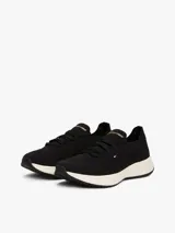 Zapatillas deportivas negras de corte bajo y estilo calcetín, con exterior de punto elástico. Cuentan con cordones, entresuela gruesa color crema y suela de goma negra. Presentan un pequeño logo de Tommy Hilfiger bordado en el lateral.