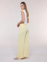 Pantalón sastrero blanco de tiro alto, corte wide leg y pierna ancha con caída fluida. Cuenta con cintura ancha lisa, cierre frontal oculto y bolsillos laterales.