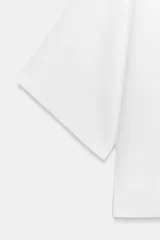 Top fluido de punto liso en color blanco, con escote en V pronunciado y mangas cortas amplias.