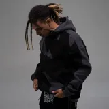 Campera con capucha confeccionada en tejido tipo polar, con diseño de bloques de color en tonos negro y gris oscuro. Presenta cierre frontal completo y ajuste regular.