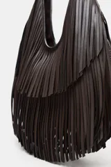 Bolso de hombro tipo shopper color marrón oscuro, con diseño de flecos en capas en toda la superficie. Cuenta con asa de hombro integrada, cierre mediante botón imantado y bolsillo interior con cremallera.