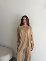 Conjunto gris melange compuesto por un buzo de cuello bote amplio y corte asimétrico con bolsillos, y un pantalón largo de corte recto y holgado.
