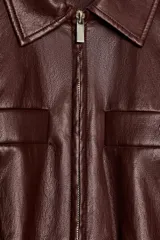 Chaqueta de efecto piel con cuello solapa, manga larga y cierre frontal con cremallera. Presenta cintura elástica que entalla la silueta y bolsillos decorativos en el frente.