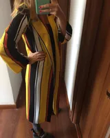 Camisola larga con rayas verticales en colores amarillo, negro, naranja y blanco, con mangas largas y aberturas laterales.