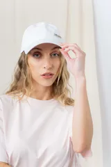 Gorra blanca de visera curva con detalle de aplique metálico con strass en el lateral izquierdo.