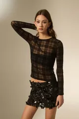 Top de manga larga confeccionado en tejido transparente con diseño de cuadros negros. Presenta un corte al cuerpo y cuello a la base.