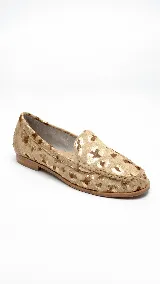 Mocasín de cuero con acabado de pelo y estampado animal print metalizado dorado, taco bajo y punta redondeada.