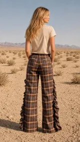 Pantalón de corte amplio con estampado a cuadros, presenta detalles de volados laterales con cordones entrecruzados que aportan textura y movimiento. Incluye bolsillos delanteros y traseros.