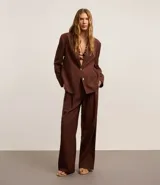 Pantalón wide leg de tiro alto color marrón chocolate, confeccionado en tejido de lino y viscosa. Incluye cinturón de cuero sintético con hebilla metálica.