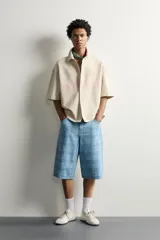 Sobrecamisa boxy fit de algodón color beige, de manga corta, con cuello solapa, cierre frontal de botones y aplicación de texto en parches rosas a contraste en el delantero.