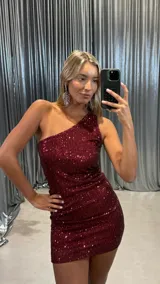 Vestido corto de fiesta confeccionado en tela con lentejuelas bordadas, de diseño ajustado al cuerpo con escote asimétrico de un solo hombro.