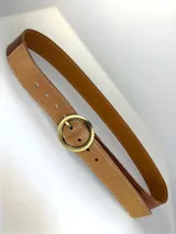 Cinturón de cuero genuino en tono tostado con acabado texturizado y detalles dorados. Presenta una hebilla circular metálica en color dorado mate.