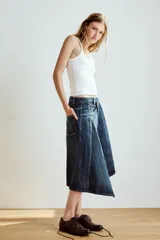 Falda midi de denim azul con tiro medio, diseño asimétrico de bajo cruzado y cinco bolsillos clásicos.