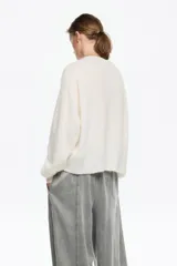 Sweater de punto en color blanco, confeccionado en una mezcla de lana y mohair. Posee un diseño de corte recto con escote en pico, mangas largas de sisa caída y acabados acanalados.