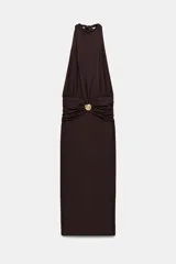 Vestido midi de cuello halter con detalle de drapeado en la cintura y broche metálico dorado en forma de caracola. Presenta cierre ajustable con lazadas en la espalda.