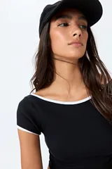 Top corto negro de punto acanalado con escote redondo, mangas cortas y ribetes blancos en cuello y mangas.