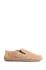 Zapatillas tipo slip-on de gamuza color beige, con diseño barefoot y suela de corcho texturizado. Presenta elásticos laterales negros para un calce fácil.