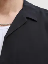 Camisa negra de manga corta con cuello cubano y cierre frontal con botones.