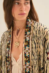 Kimono de corte holgado con estampado animal print tipo tigre, con bordes frontales decorados con pedrería y bordados artesanales. Presenta mangas anchas y forro interior.