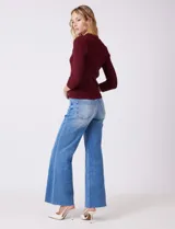 Buzo de tejido acanalado marca Rio & Rian, color beige, con cuello tipo polo con solapa y botones frontales, y mangas tres cuartos.