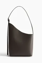 Bolso shopper asimétrico de tejido revestido color marrón oscuro, con diseño de corte diagonal en la parte superior, correa de hombro ajustable y detalle de tira colgante.