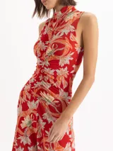 Vestido midi sin mangas con estampado floral en tonos rojos y celestes, cuello alto y detalle fruncido en el centro delantero.