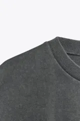 Camiseta gris con efecto lavado, cuello redondo con ribete y mangas cortas tipo capa.