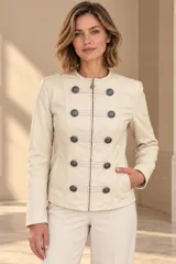 Campera de cuero ovino color beige, estilo napoleón, con cuello redondo, cierre frontal y botones metálicos decorativos en formato militar.