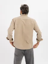 Camisa de manga larga confeccionada en pana de algodón, con cuello clásico, cierre frontal de botones y bolsillo en el pecho.