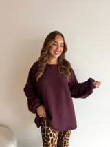 Buzo de punto color marrón chocolate, con cuello redondo, mangas largas con puños elásticos y diseño holgado de largo extendido.
