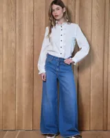 Jean de corte wide leg, color azul medio, con diseño de pierna ancha y ruedo desflecado.