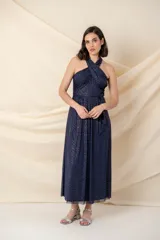 Vestido largo de tul azul marino con destellos dorados, escote halter cruzado y drapeado, con corte en la cintura y falda amplia.