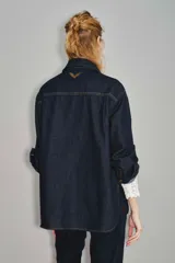 Camisa de jean de corte entallado con cierre frontal de botones, cuello clásico y mangas largas con puños ajustables. Presenta un diseño versátil ideal para combinar con diversas prendas.